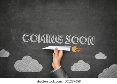 Coming soon concept on black blackboard with businessman hand holding paper plane - Shutterstock ID 301287659
