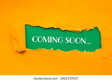 Coming soon words written on torn orange paper with green background. Conceptual coming soon symbol. Copy space.