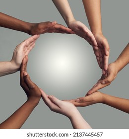 Coming Together To Form One. Cropped Shot Of A Group Of Hands Linking Together To Form A Circle Against A Grey Background.