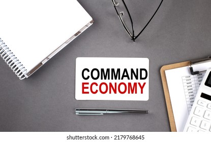 COMMAND ECONOMY Text Written On Card With Notebook And Clipboard, Grey Background