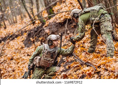 Command Rangers During The Military Operation. Soldier Giving Hand And Helping To Climb. Help, Support, Assistance In A Dangerous Situation