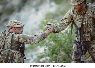 Command Rangers During The Military Operation. Soldiers Climbing On Mountain, One Of Them Giving Hand And Helping To Climb. Help, Support, Assistance In A Dangerous Situation