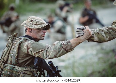 Command Rangers During The Military Operation. Soldiers Climbing On Mountain, One Of Them Giving Hand And Helping To Climb. Help, Support, Assistance In A Dangerous Situation