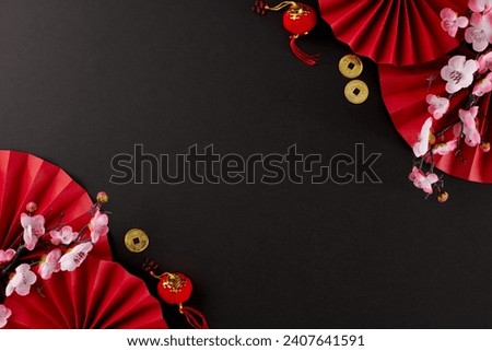 Commencing the celebrations for Chinese New Year or Lunar New Year. Top view photo of folding fans, sakura, traditional coins, lanterns on black background with promo spot
