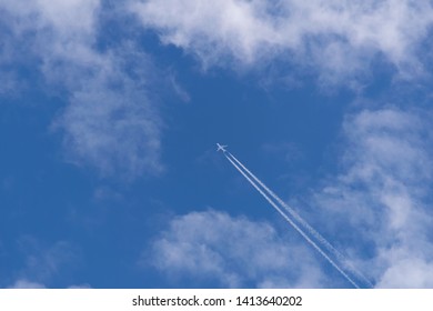 A commercial aeroplane speeds through the wispy clouds on a bright blue sky day - Powered by Shutterstock