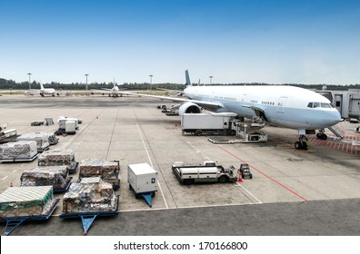 A Commercial Aircraft Being Serviced On The Tarmac Of An International Airport.