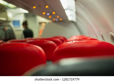 Commercial Aircraft Cabin With Rows Of Seats Down The Aisle,Interior Of Airplane With Passengers On Seats And Stewardess Walking The Aisle.