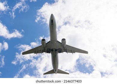 A Commercial Aircraft Landing At An Airport Against An Afternoon Sky