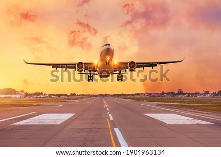 Commercial airliner passenger plane fly down over landing at sunset