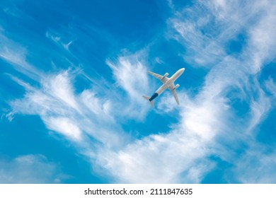 Commercial airplane flying against blue cloudscape sky. Jet plane in high flight. Airliner flying under the clouds. Aircraft flying in the clouds. Bottom view
