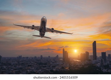 Commercial airplane flying over city with skyscrapers at evening sunset golden hour - Powered by Shutterstock