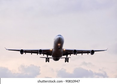 Commercial airplane with four engines in final approach front view