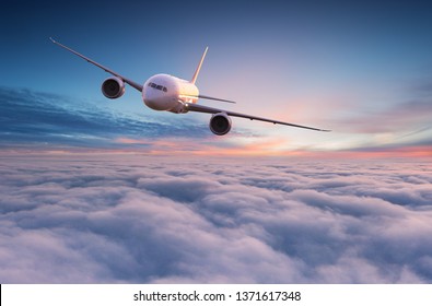 Commercial Airplane Jetliner Flying Above Dramatic Clouds In Beautiful Sunset Light. Travel Concept.