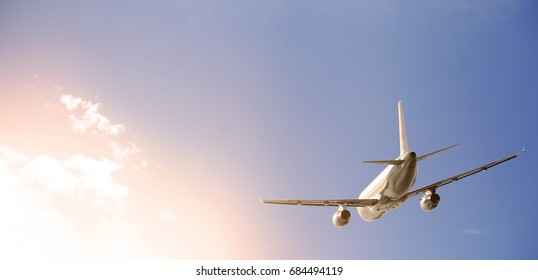 Commercial Airplane Jumbo Jet Flying Above Clouds In A Blue Sky  At Sunset. 