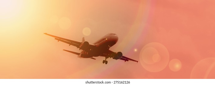 Commercial Airplane Landing At Sunset.