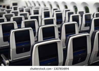  commercial airplane seats viewed from the rear. Inflight entertainment displays.