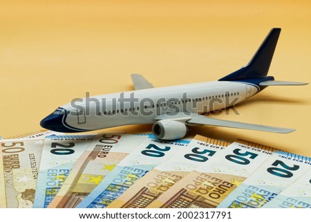 Commercial airplane toy and a pile of Euro banknotes. Flights cost concept