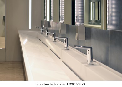 Commercial Bathroom, Sink And Containers For Antibacterial Soap Antiseptic In A Public Toilet. Coronavirus And Hand Washing Concept.