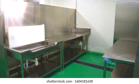 Commercial, Central Kitchen Food Factory Preparation Area With Stainless Steel Sink, Work Table And Chopping Board. Green Floor