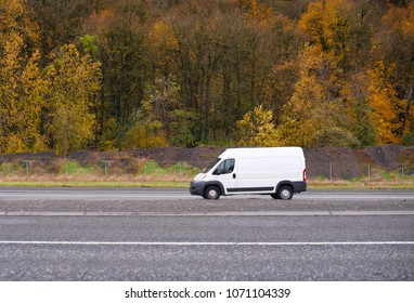 Commercial compact cargo mini van vehicle for small business going on the entrance to interstate road with autumn yellow gold trees on the background