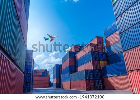Commercial international plane flying above shipyard harbor warehouse containers storage transportation export distributed commerce and logistic business. 