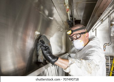 Commercial Kitchen Worker Washing Up At Sink In Professional Kitchen