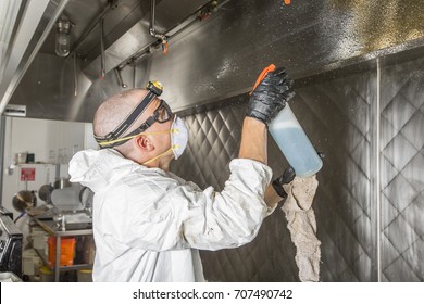 Commercial Kitchen Worker Washing Up At Sink In Professional Kitchen