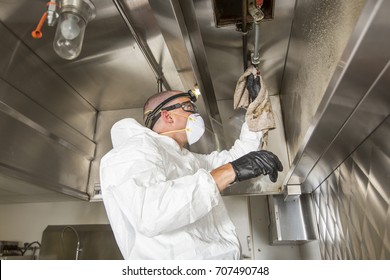 Commercial Kitchen Worker Washing Up At Sink In Professional Kitchen