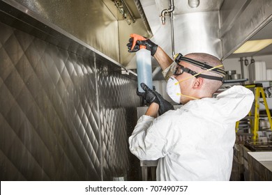 Commercial Kitchen Worker Washing Up At Sink In Professional Kitchen