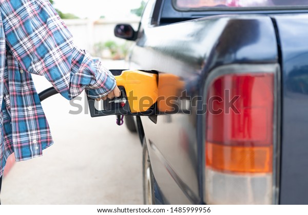 Commercial petroleum filling;woman\
service transfer gas from gas station to the black car\
.