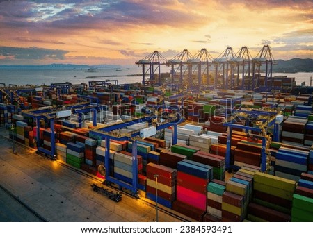 A commercial port with stacks of containers and loading cranes during sunset time
