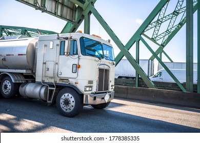 Commercial Professional Transportation Old Fashioned Retro Cabover Industrial White Diesel Big Rig Semi Truck Transporting Fuel In Tank Semi Trailer Running On The Truss Arched Interstate Bridge