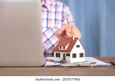 Commercial Real Estate Salesperson Fingering The House Model Next To The Computer