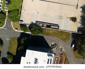 Commercial rooftop featuring multiple large hvac cooling units and ventilation systems, seen from an aerial perspective over an urban environment with adjacent parking, roads, and green spaces. New yo