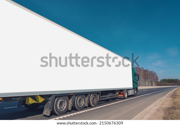 Commercial truck with long empty white\
board for mock up driving at asphalt road on\
highway