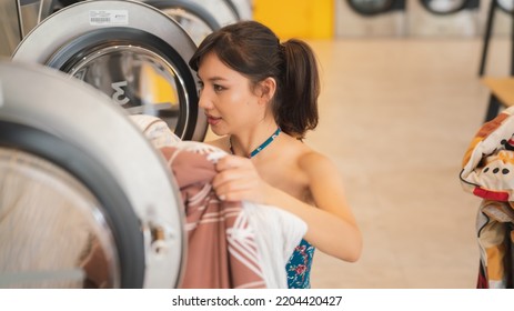 Commercial Washing Machine Business.A Beautiful Woman Uses A Washing Machine At A Store.The Modern Washing Machine Utility Is An Electrical Appliance.Clothing Cleaning Industry