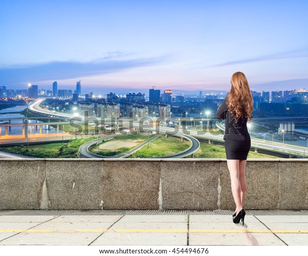 A\
commercial woman looks down at the city\'s\
overpass