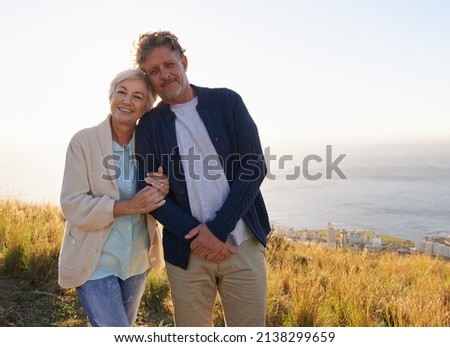Committed to loving one another. View of a senior couple standing on a hillside together.