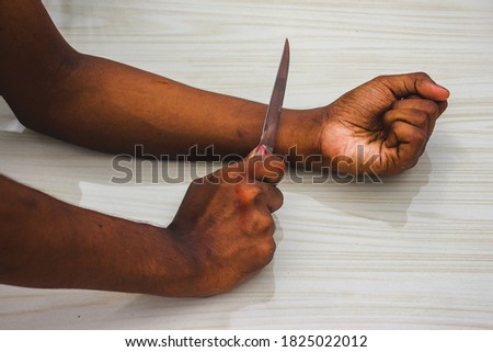 Committed Suicide Concept - Man want to commit suicide by cutting his veins with knife in isolated on floor background. man suicide by knife cutting a wrist,Depressed & Sad love.