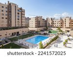 Common areas of an urbanization with swimming pools, benches and flower boxes and a lot of grass and tennis courts