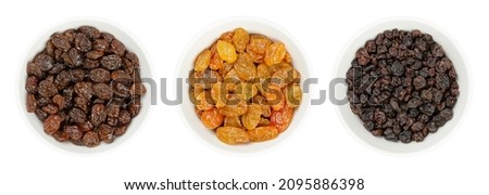 Common commercial raisins, golden raisins (Sultanas), and small currants (Zante currants or Black Corinth), in white bowls. Dried seedless grapes, to be eaten raw or used in cooking and baking. Photo.