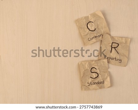 Common Reporting Standard (CRS) text on crumpled paper notes on wooden desk. Concept of financial regulations, tax transparency, global banking standards, and the administrative challenges of international tax compliance