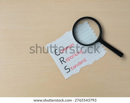 Common reporting standard (CRS) text on a piece of paper with magnifying glass. Concept of financial transparency, international tax regulations, and global information exchange for tax purposes