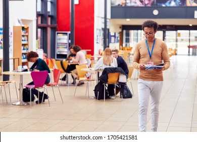 Communal Area Of Busy College Campus With Tutor And Students Working At Tables