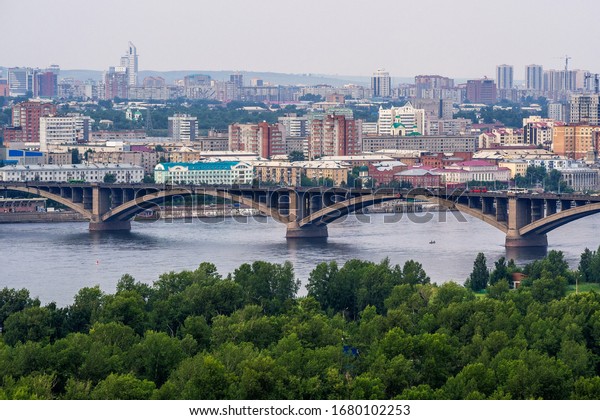 Communal bridge over the river. Yenisei and\
Island of Rest in the foreground. Large forest in the foreground\
photo, Yenisei and the communal bridge, as well as the center of\
Krasnoyarsk