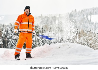 Communal service worker in uniform with a shovel clears snow in winter - Powered by Shutterstock