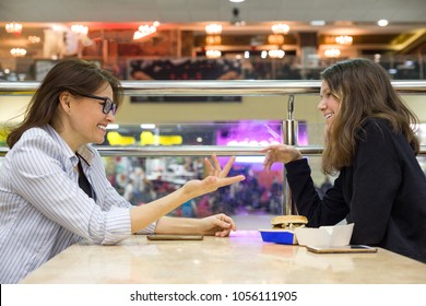 Communication Of Adult Mother And Teen Daughter. Background Table In Cafe, In The Shopping Mall Entertainment Center.