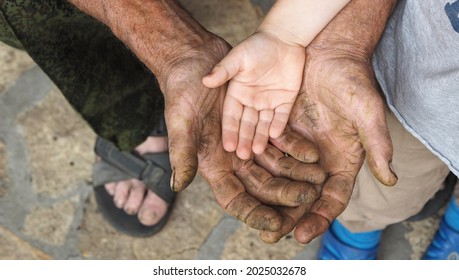 Communication and continuity of two generations. Grandfather and grandson. A child's hand rests on the rough calloused hand of a working man.