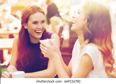 Communication And Friendship Concept - Smiling Young Women With Coffee Cups At Cafe