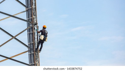 Communication Maintenance. Technician Climbing On Telecom Tower Antenna Against Blue Sky Background, Copy Space.